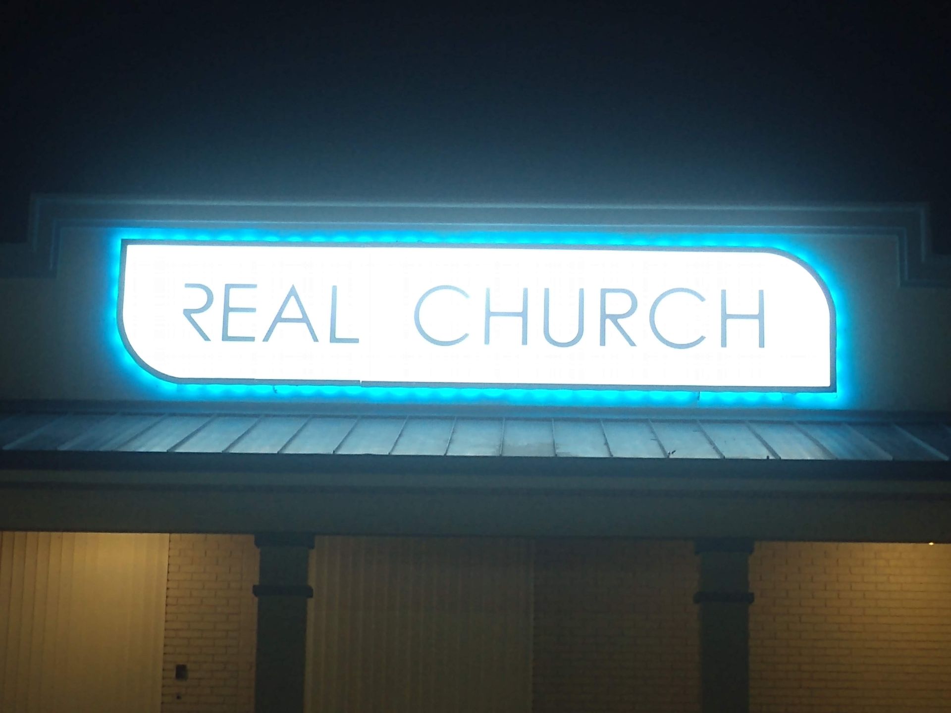 A sign for the real church is lit up at night