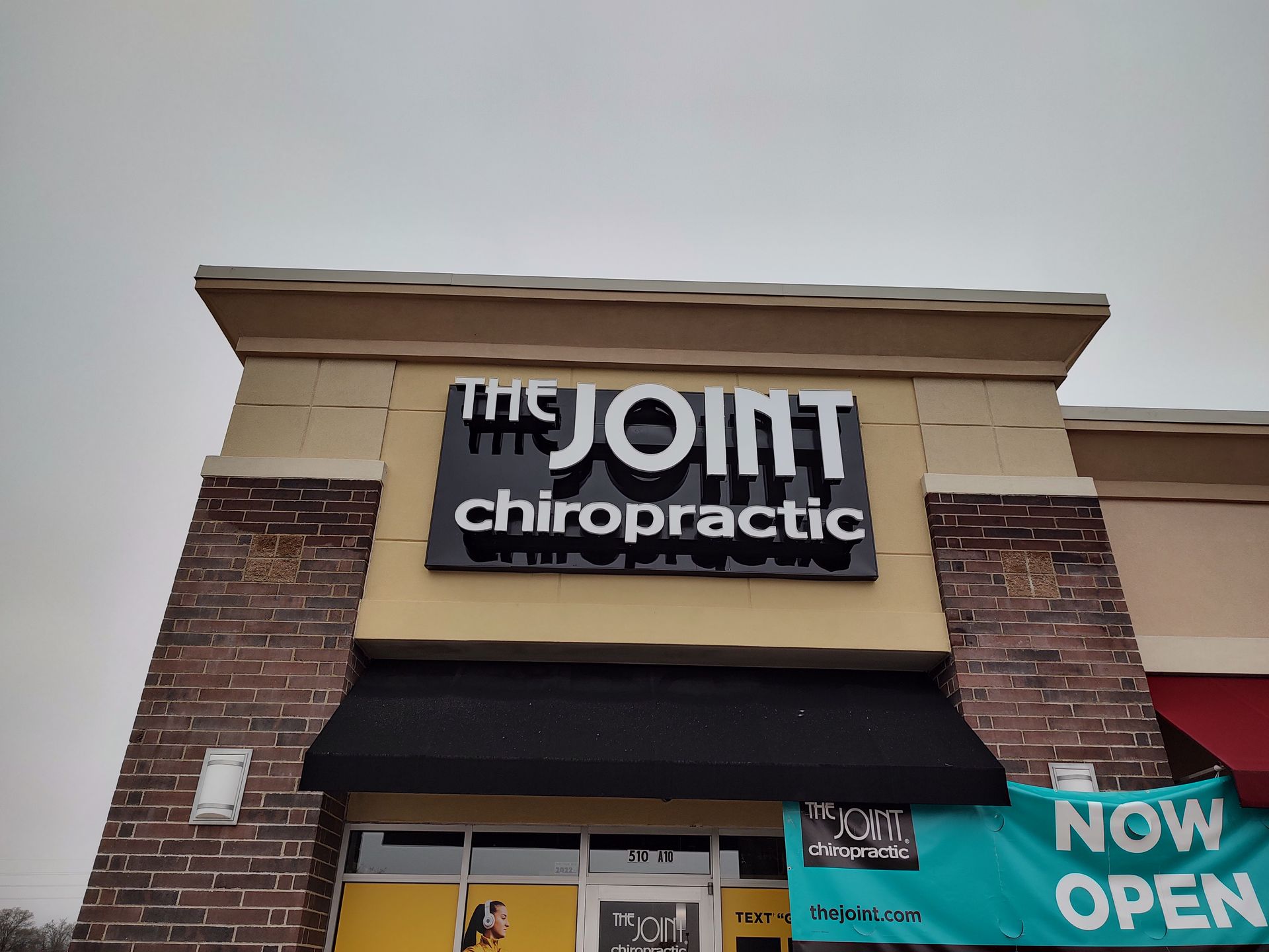 A brick building with a sign that says the joint chiropractic