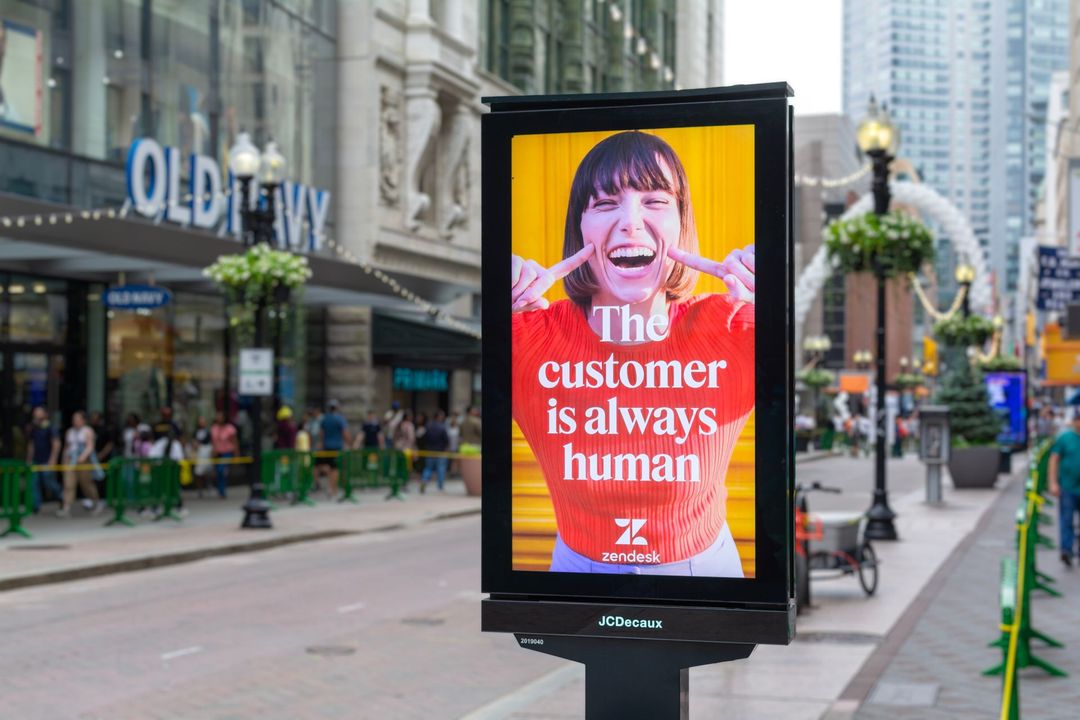 Street-level ad: Woman with open mouth and fingers on cheeks.