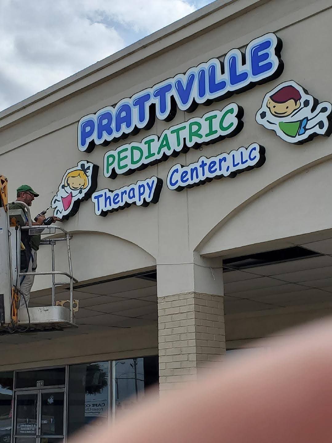 A man is painting a sign for prattville pediatric therapy center