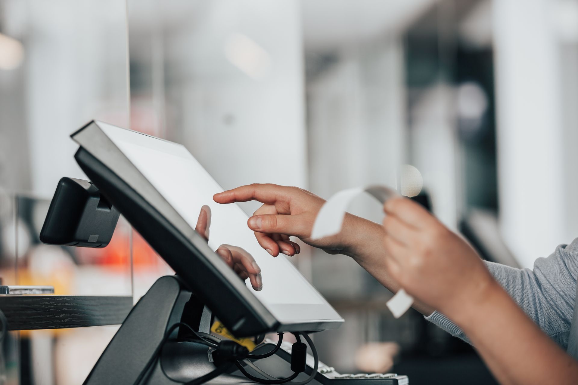 A saleswoman doing a process payment on a touchscreen POS, counting a sale with a receipt.