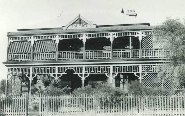 A black and white photo of a house with a fence around it