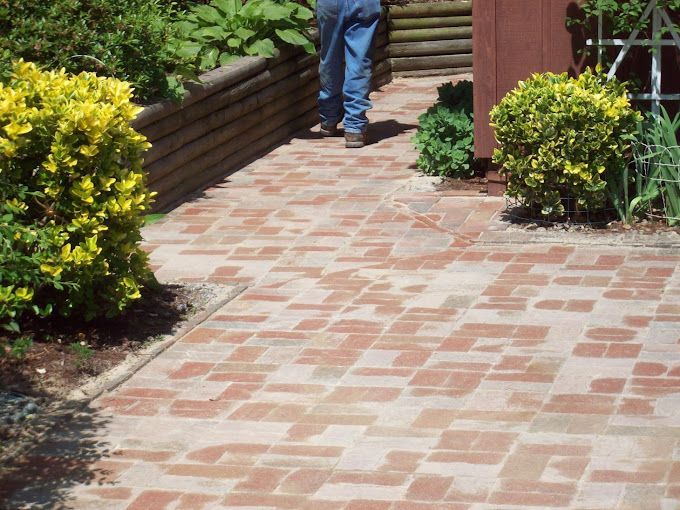 A brick walkway leading to a house with a diamond in the middle.