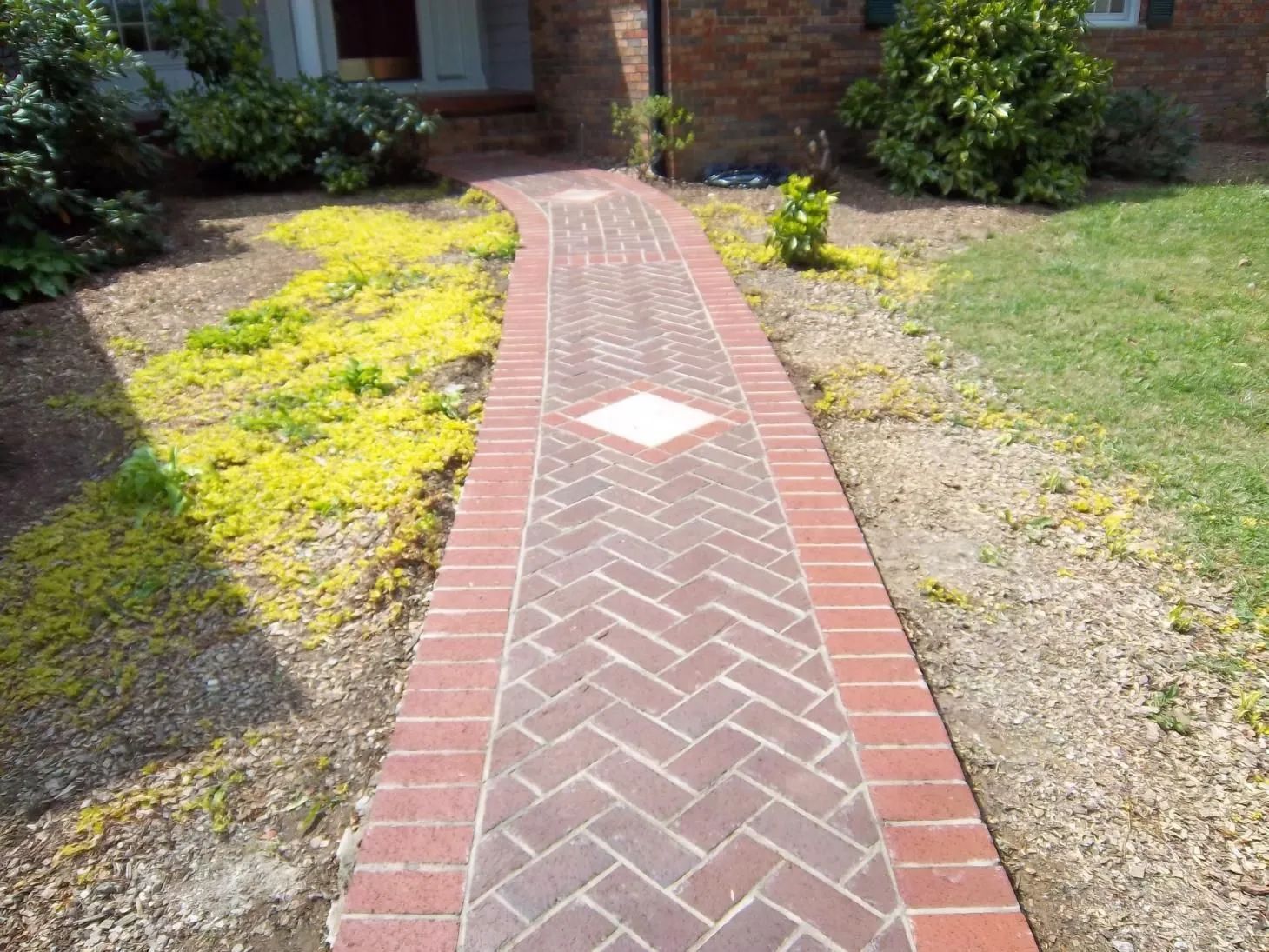 A brick walkway leading to a house with a diamond in the middle.