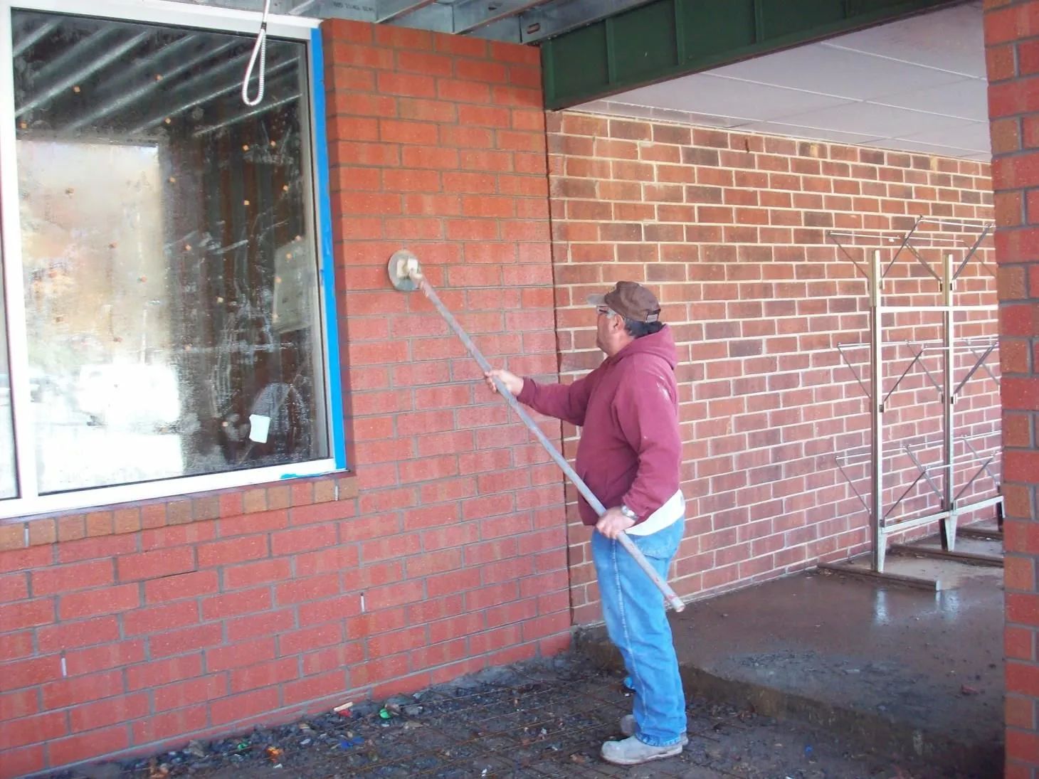 A person is standing in front of a brick wall.