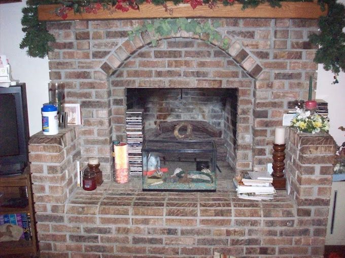 A man is cleaning a brick wall with a broom.