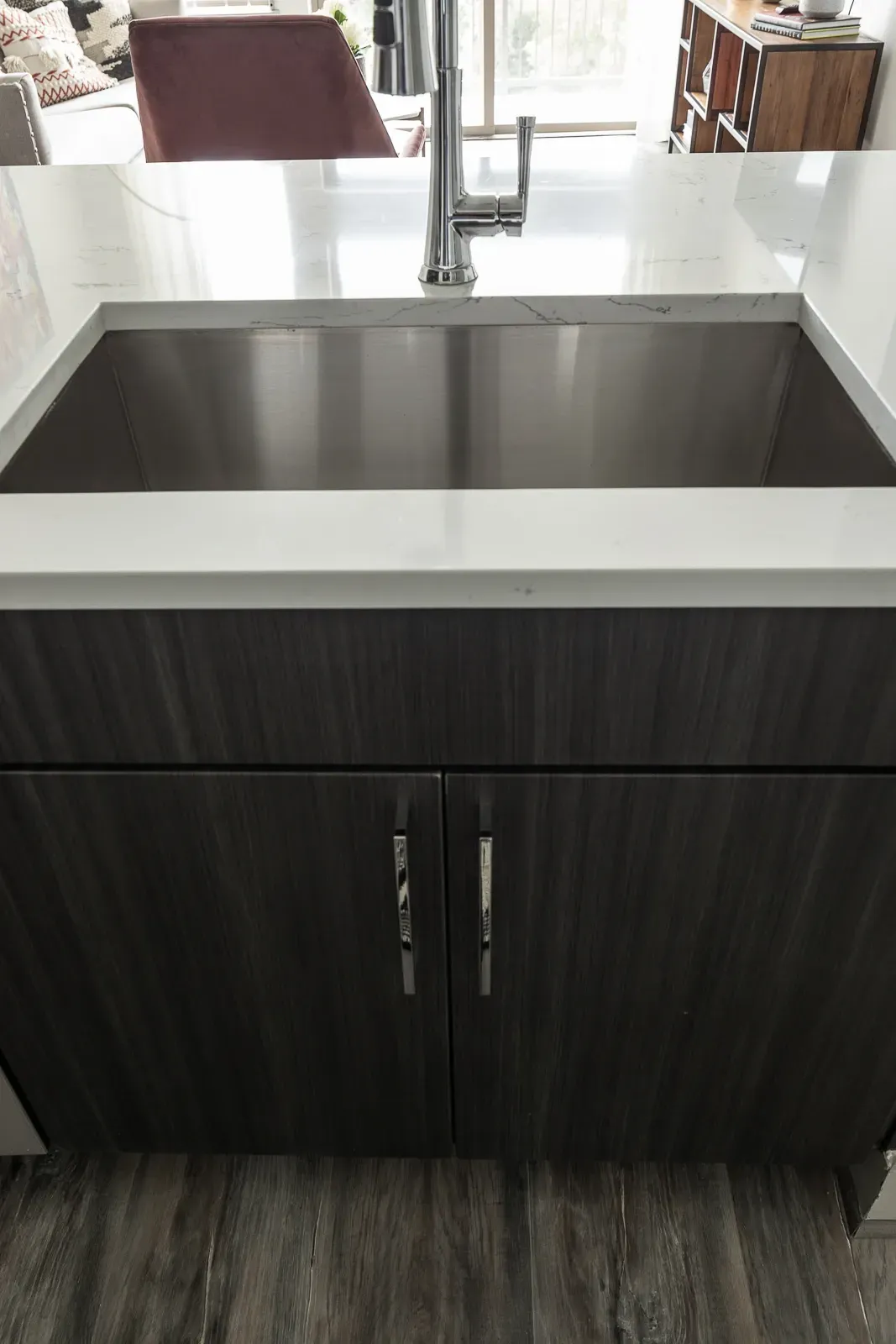 Stainless steel kitchen sink with modern faucet and dark wood cabinets.