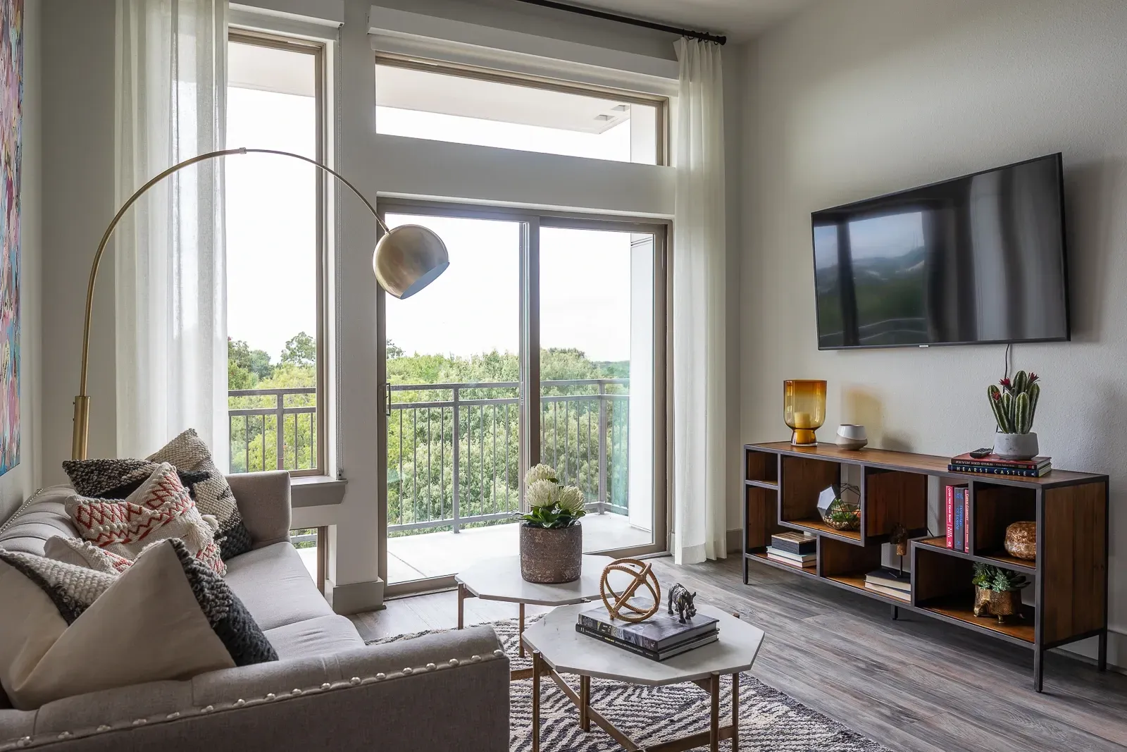Modern living room with sofa, coffee table, TV, and balcony access.
