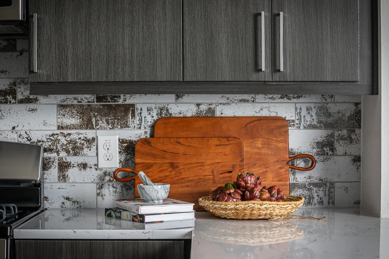 Kitchen counter with cutting boards, artichokes, and marble mortar and pestle.