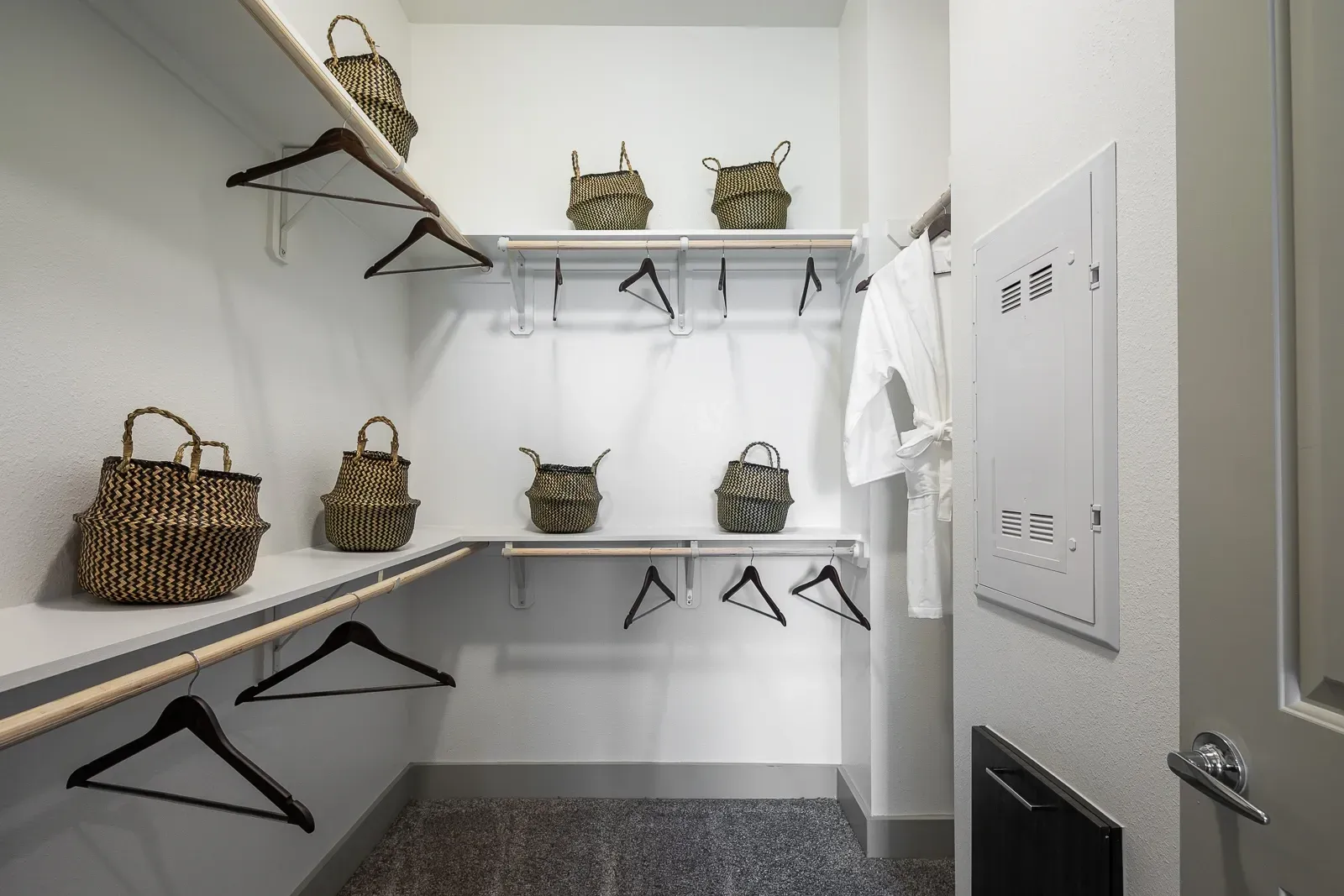 Spacious walk-in closet with built-in shelving and hanging rods, decorated with woven baskets.