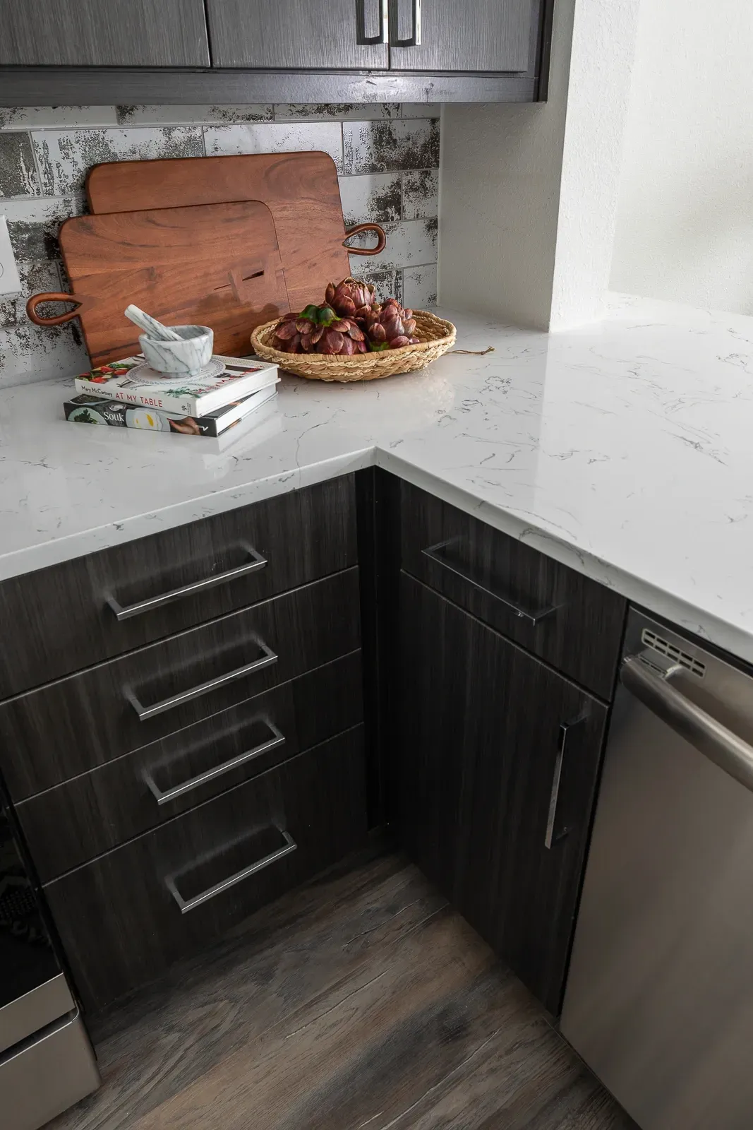 Kitchen countertop with wood cutting boards, mortar and pestle, books, and artichokes.