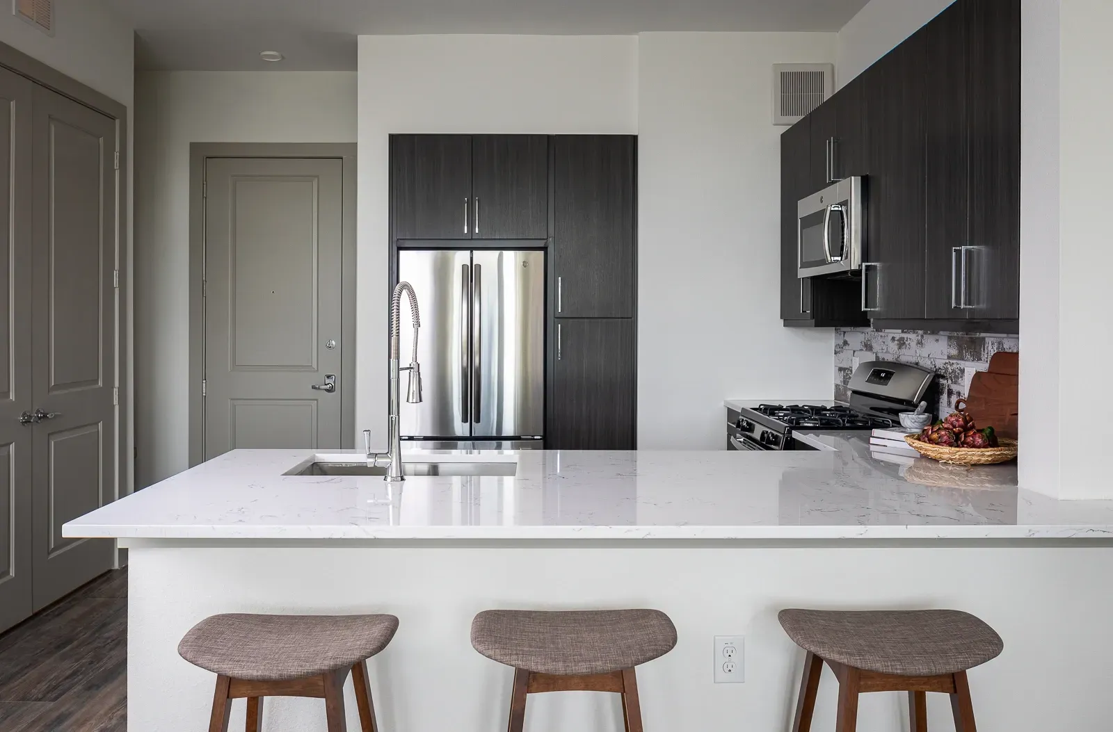 Modern kitchen with quartz countertops, stainless steel appliances, and bar seating.