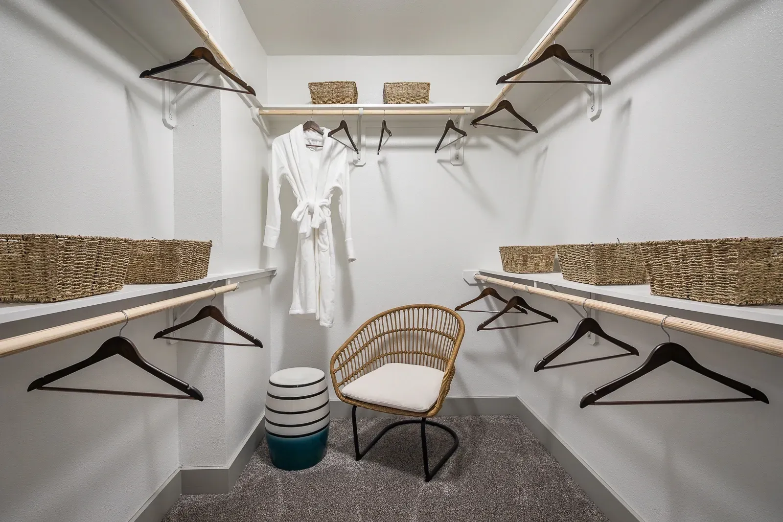 Spacious walk-in closet with white robe, chair, and baskets.