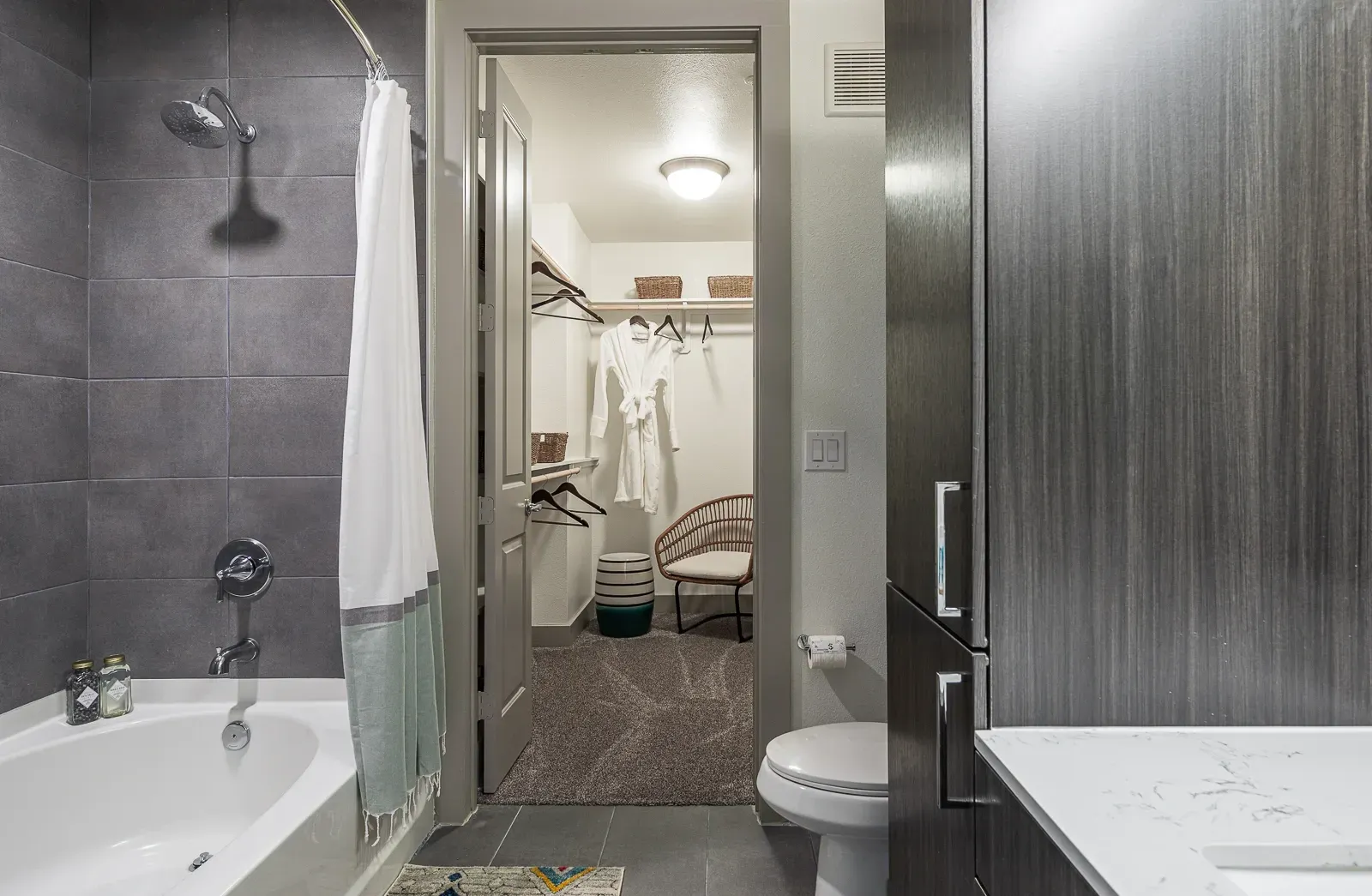 Modern bathroom with a walk-in closet, bathtub, and vanity.