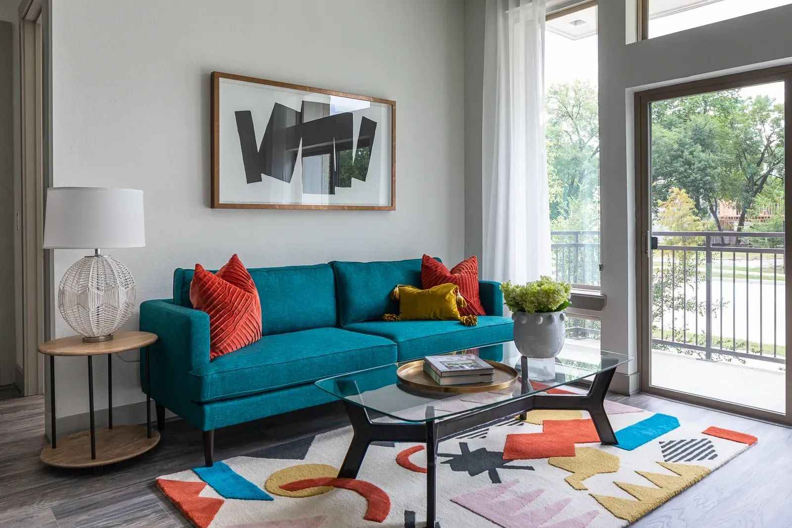 Modern living room with teal sofa, abstract art, and colorful rug.