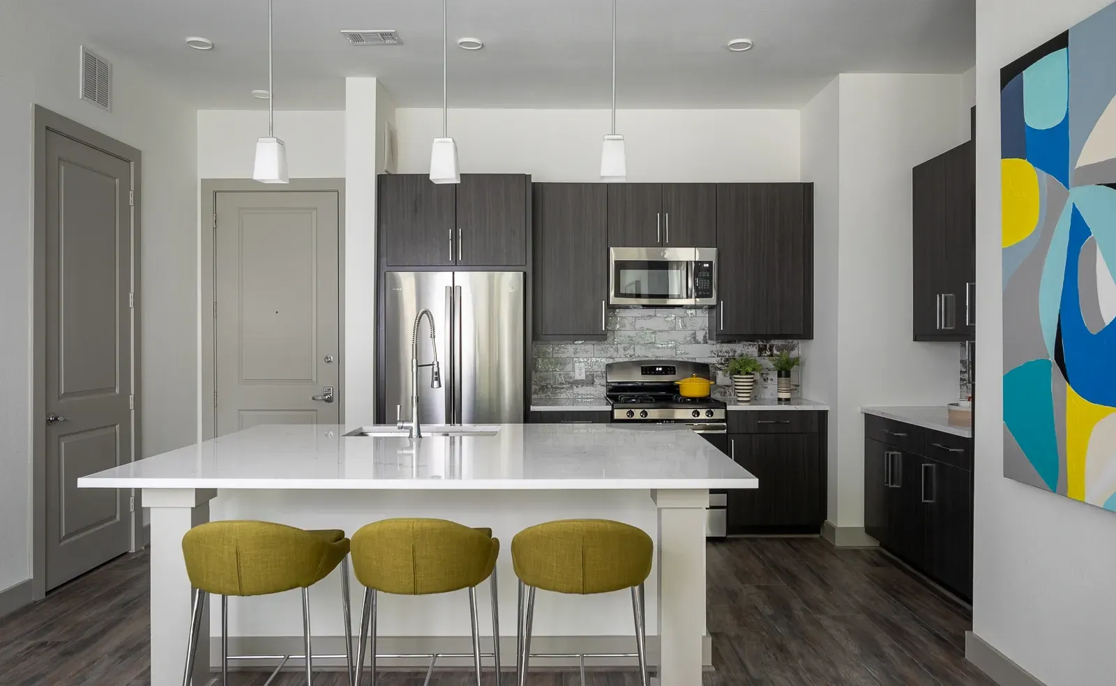 Modern kitchen with a large island, stainless steel appliances, and dark wood cabinets.