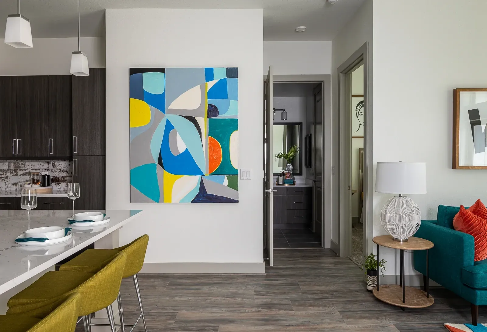Modern living room and kitchen area with abstract art and island seating.