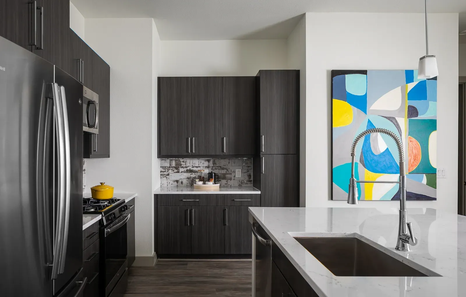 Modern kitchen with dark wood cabinets, stainless steel appliances, and a large island with a sink.