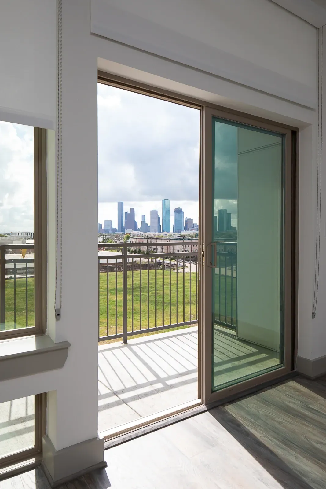 View of the city skyline from an apartment balcony with sliding glass doors.