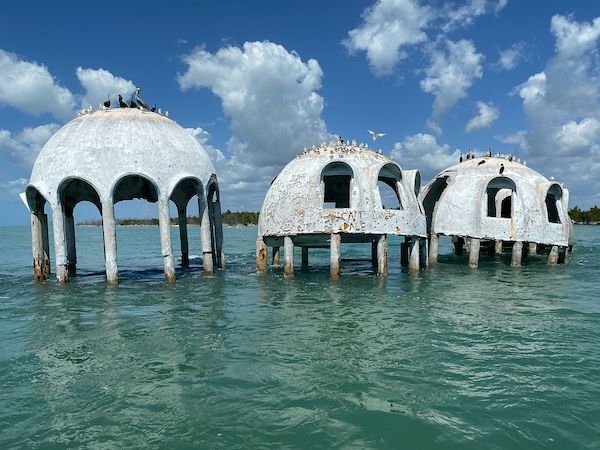 Three dome shaped buildings are floating in the ocean