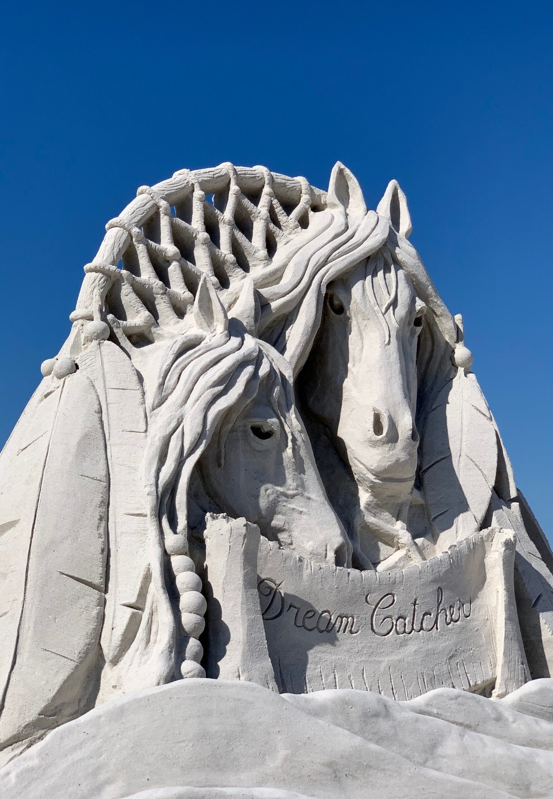 A sand sculpture of two horses with a sign that says princess garden