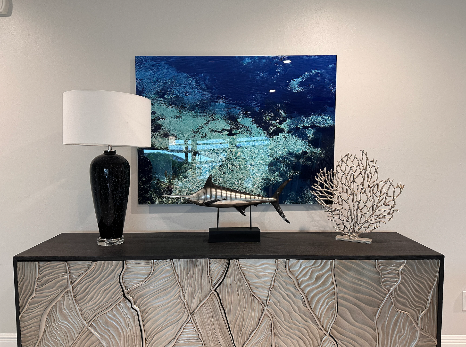 A painting of a fish is hanging on a wall above a table.