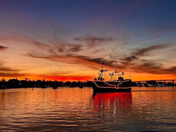 A pirate ship is floating on top of a body of water at sunset.