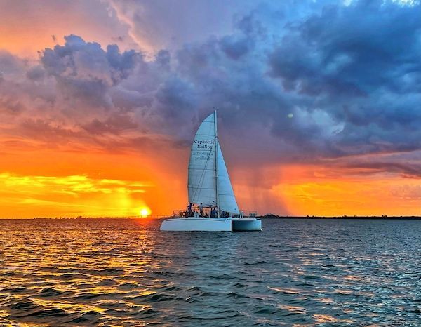 A sailboat is floating on top of a body of water at sunset.