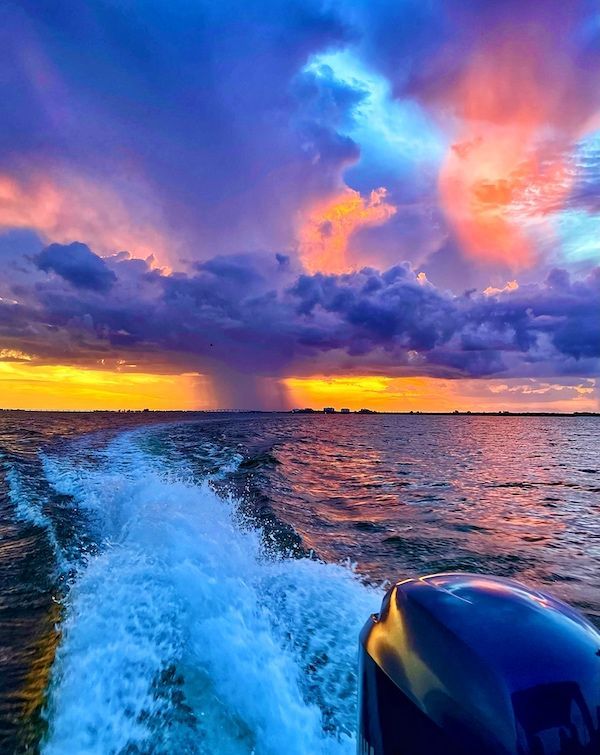 A boat is going through the ocean at sunset.