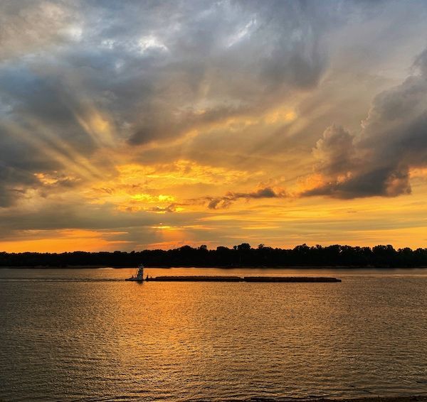 A sunset over a body of water with a boat in the distance
