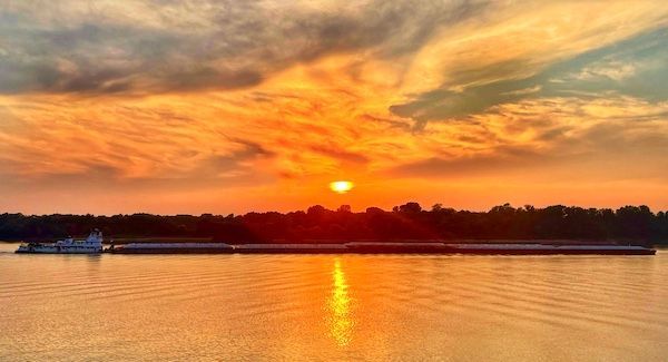 A sunset over a body of water with a boat in the foreground.