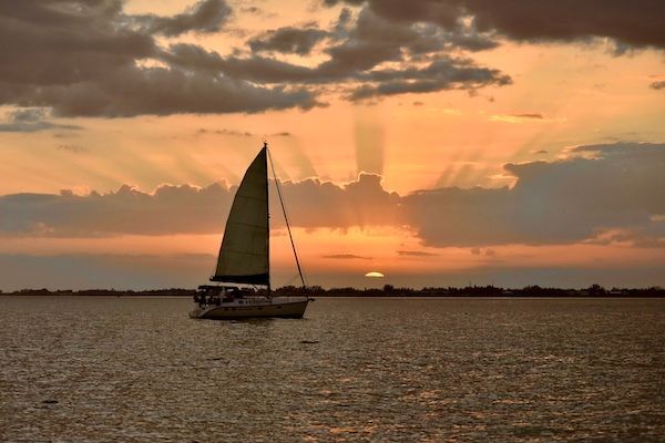 A sailboat is floating on the water at sunset