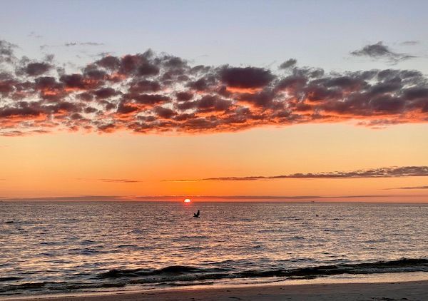 A sunset over the ocean with a boat in the distance.