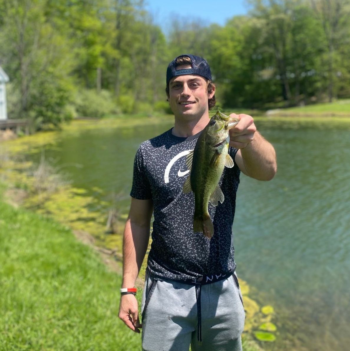 A man is holding a fish in his hand in front of a lake.