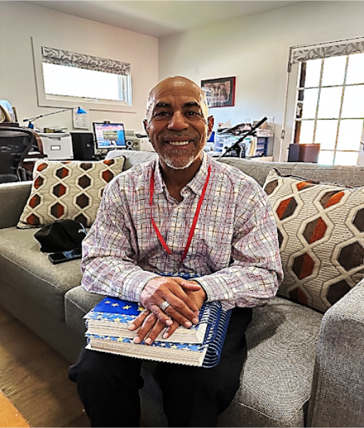Marchell smiling, sitting on a couch, holding notebooks
