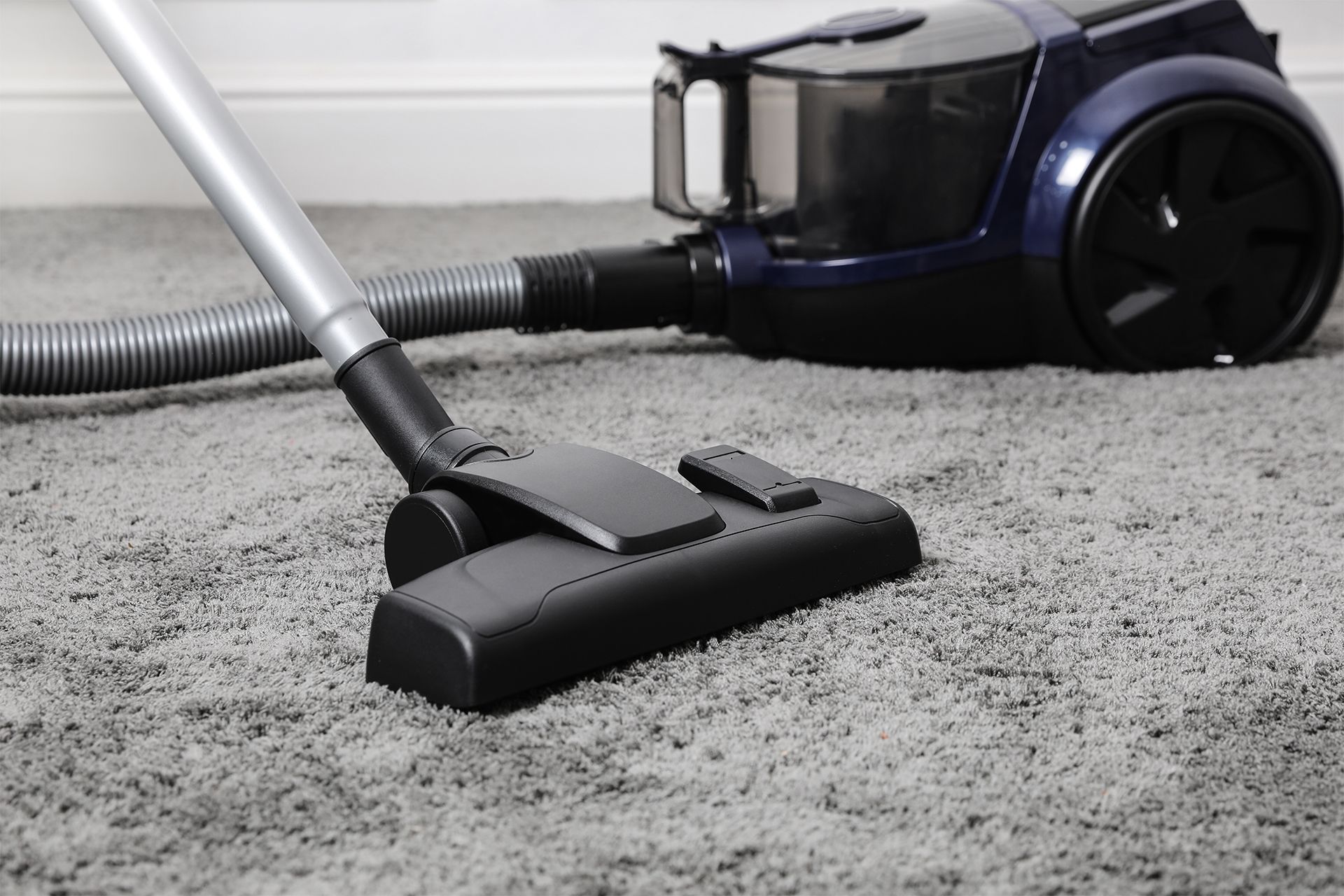Vacuum cleaner cleaning gray carpet.