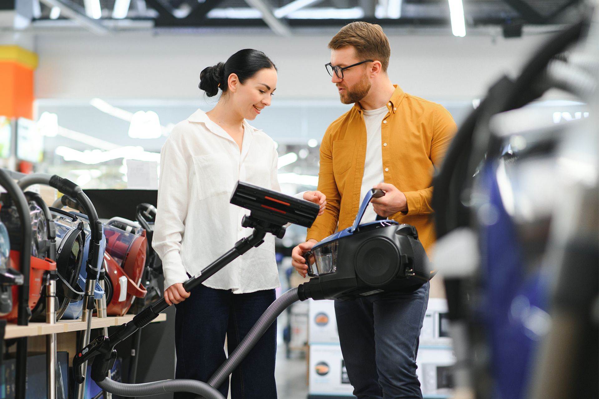 Couple in examining a vacuum cleaner.