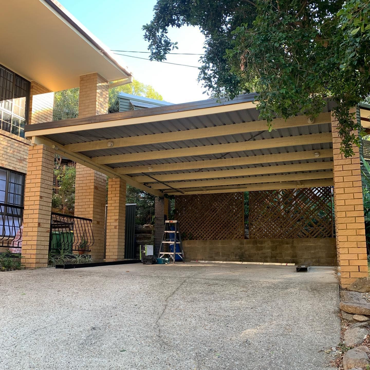 There is a carport in front of a brick house.