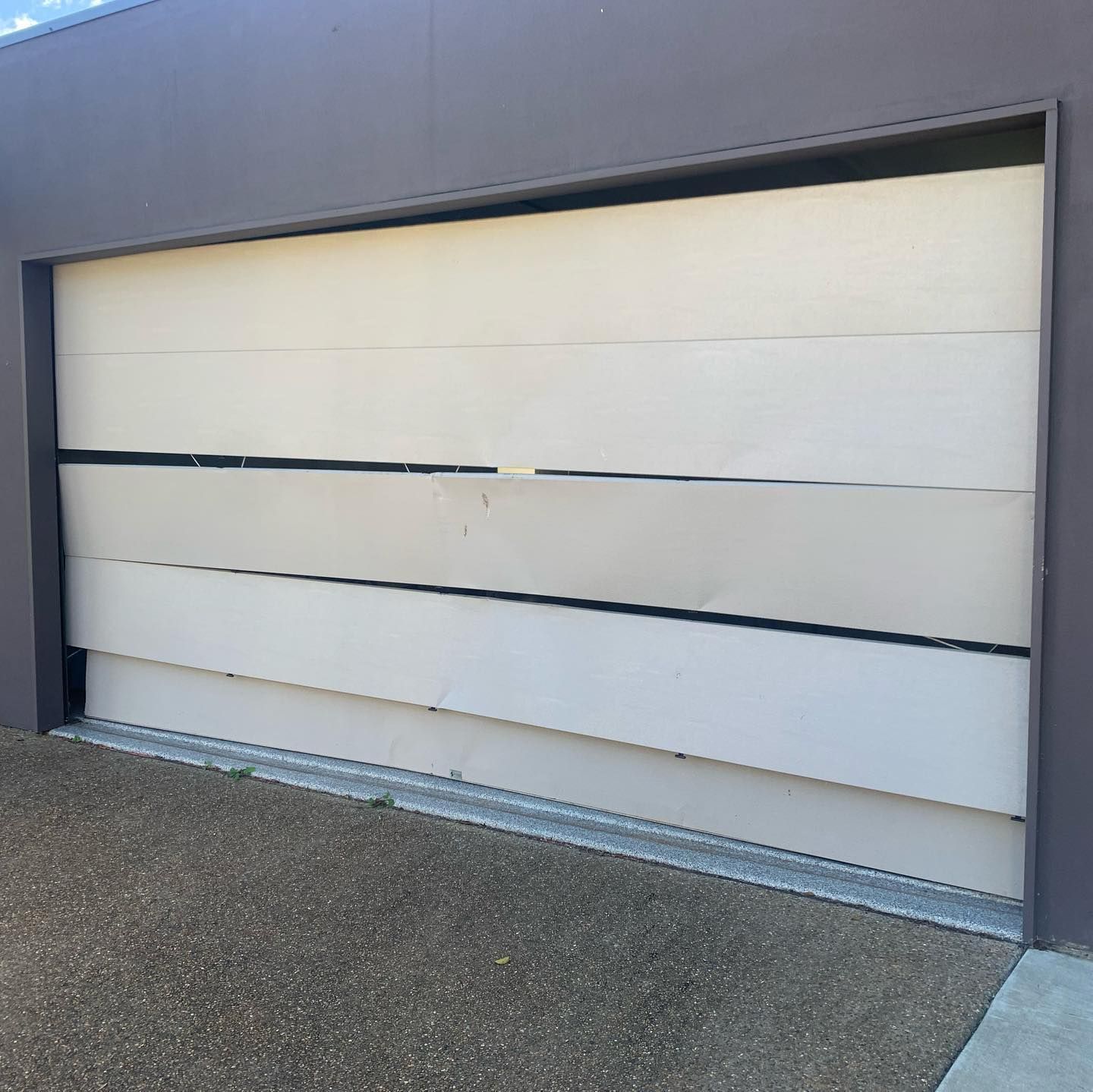 A white garage door with a black stripe on the side of it.