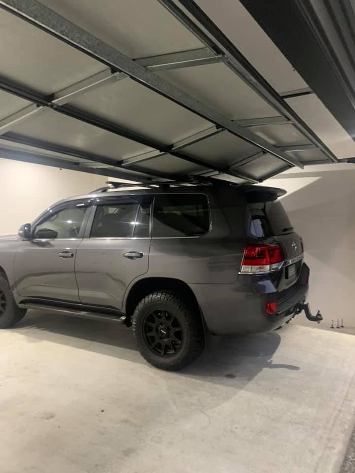 A toyota land cruiser is parked in a garage with a surfboard on top of it.