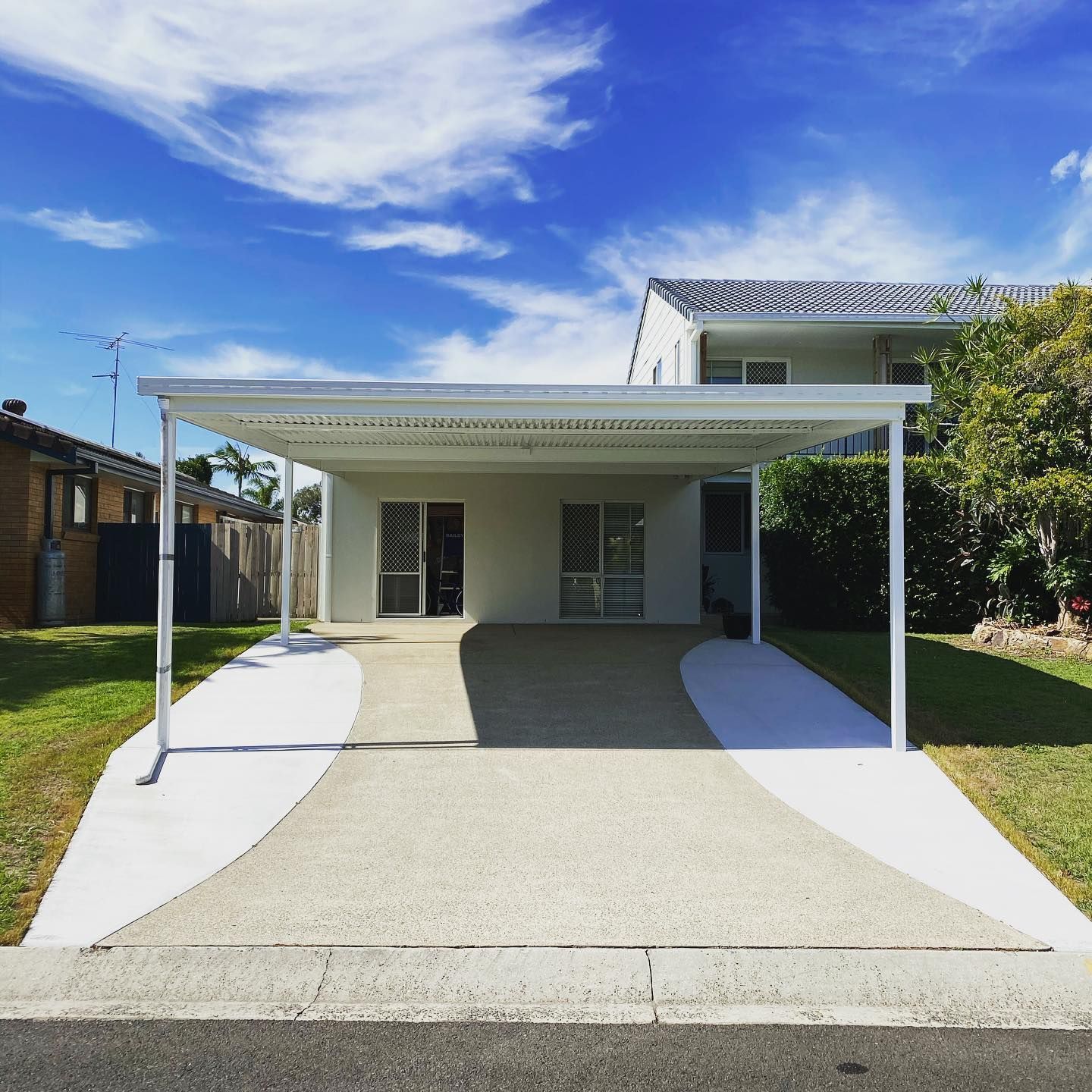 A white house with a covered driveway in front of it