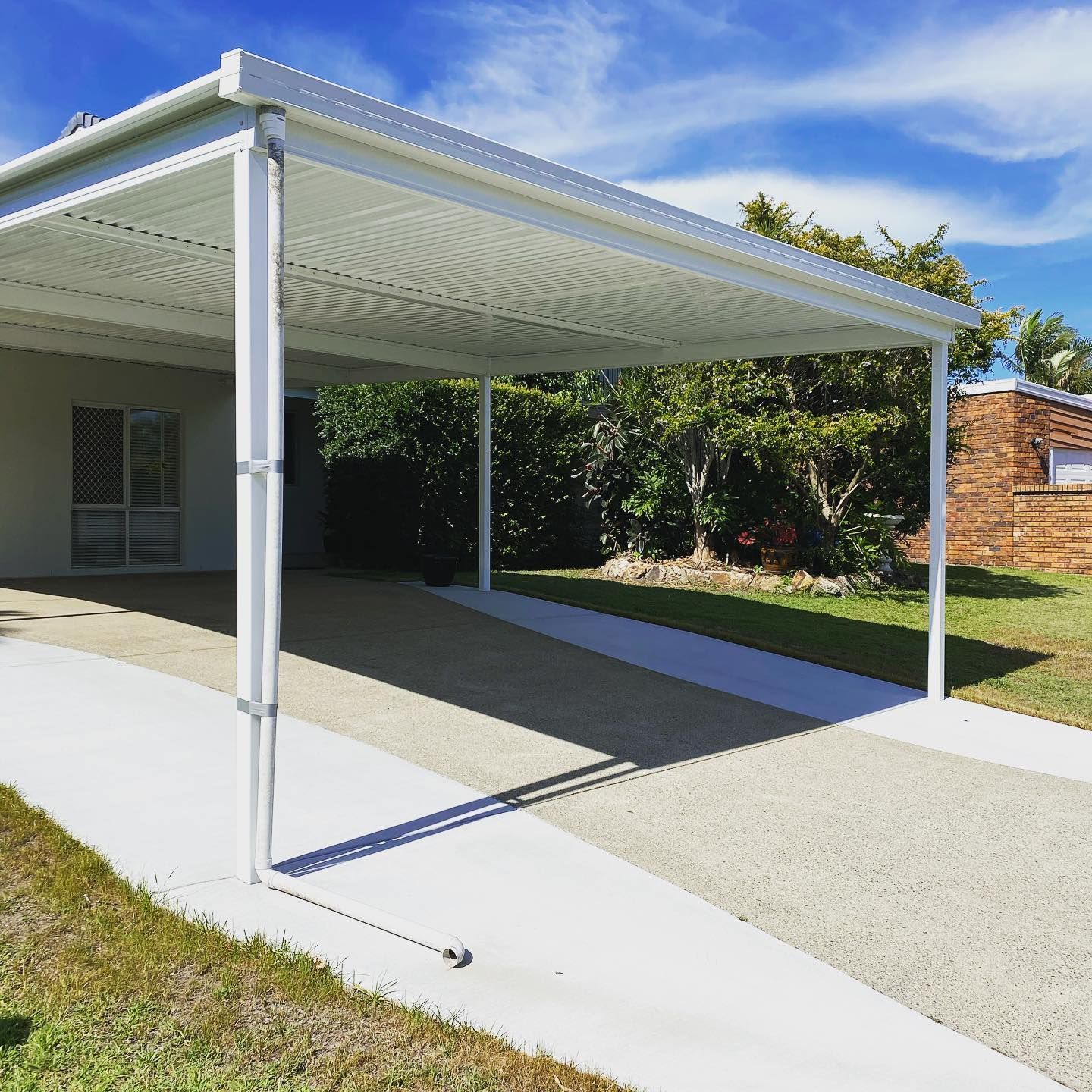 A white carport in front of a house on a sunny day