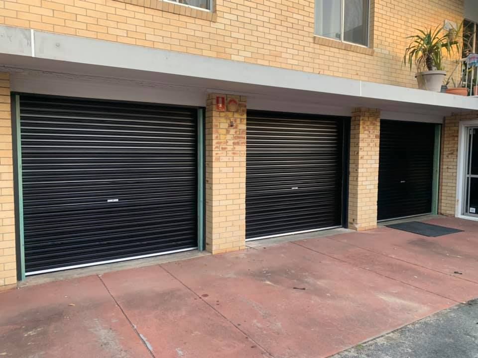 A row of garage doors on the side of a brick building.