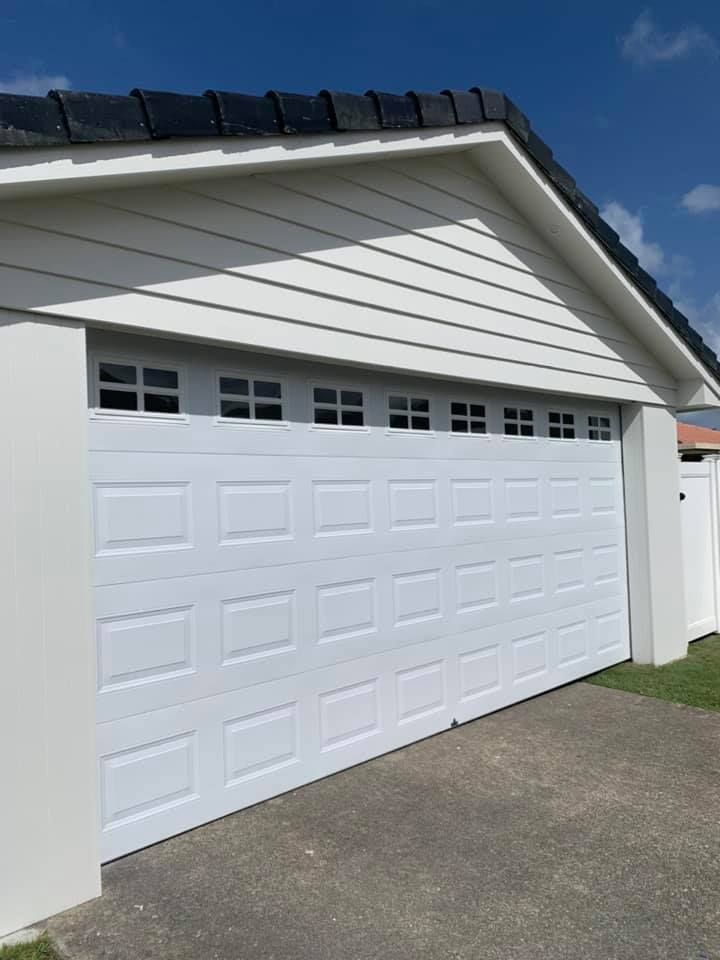 A white garage door is sitting on the side of a house.