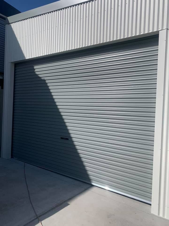 A garage door with a white wall and a gray garage door.