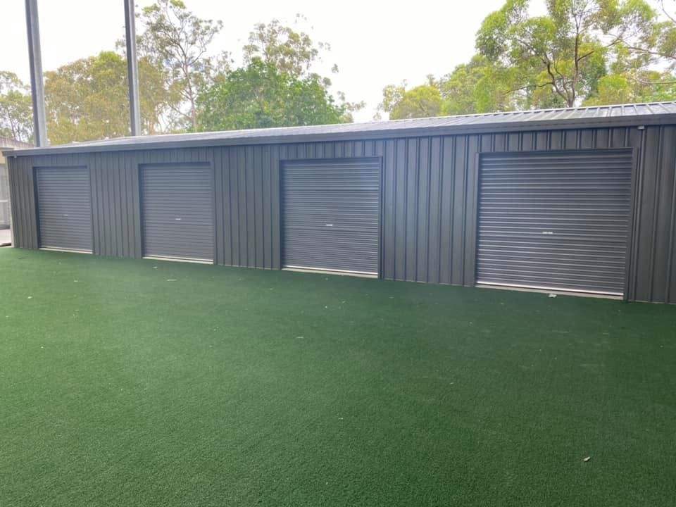 A row of garage doors sitting on top of a lush green field