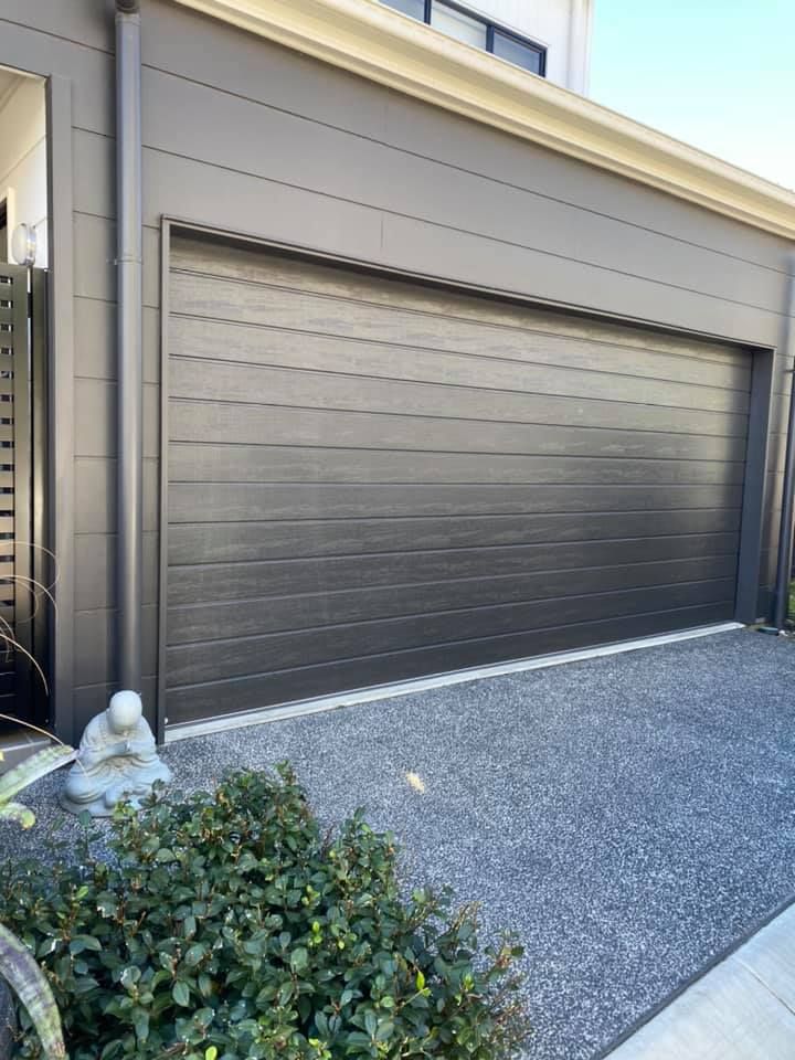 A black garage door is sitting in front of a house.