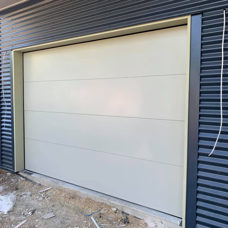 A white garage door is sitting on the side of a building.