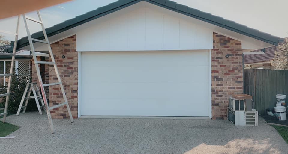 A white garage door is being installed on a brick house.