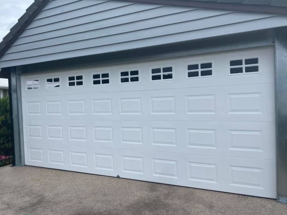 A white garage door is sitting on the side of a house.